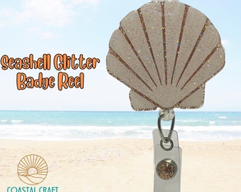 Puede incluir: Carrete de insignia de brillo de concha marina con una concha marina blanca con brillo dorado y un carrete de insignia retráctil de brillo dorado. La concha marina está sobre un fondo de cielo azul y océano.