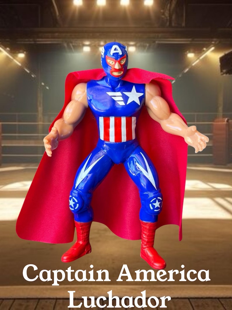 Puede incluir: Una figura de acci&oacute;n de pl&aacute;stico de un luchador que lleva una m&aacute;scara azul con una letra A blanca, un traje azul y rojo con una estrella y rayas, y una capa roja larga. La figura tiene brazos y piernas musculosos, botas rojas y rodilleras con estrellas.