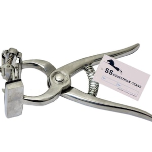 May include: A silver metal livestock branding tool with a spring-loaded handle and a square branding head. The tool is used to mark animals with a hot iron.