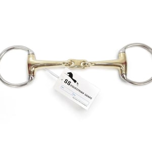 Op de afbeelding: Een paardenbit met een goudkleurig middenstuk en zilverkleurige ringen aan elk uiteinde. Een wit label met de tekst "SS Equestrian Gears" is aan het bit bevestigd.