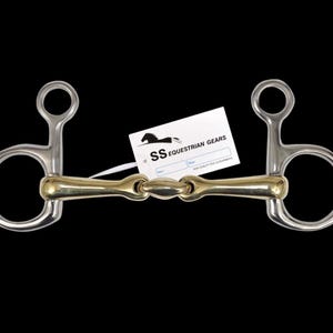 Può includere: Un morso per cavallo in acciaio inossidabile e ottone. Il morso ha un giunto centrale e due anelli su entrambi i lati. Un'etichetta bianca con la scritta "SS Equestrian Gears" è attaccata.