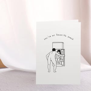 Pu&ograve; includere: Un'illustrazione in bianco e nero di una persona che apre la porta di un frigorifero. Il testo "you're my favorite snack" &egrave; scritto sulla carta.