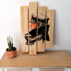 Könnte beinhalten: Ein Wandkunstwerk aus Holz mit einer Schwarzweißillustration einer Person mit Hut und Mantel. Die Illustration ist in fünf vertikale Abschnitte unterteilt.