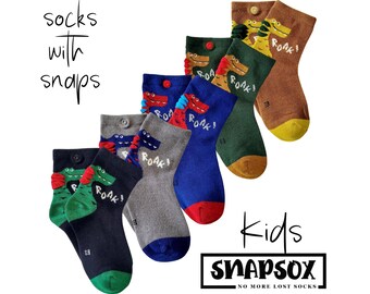 Puede incluir: Una colección de calcetines infantiles con cierres de broche, con diseños de dinosaurios de dibujos animados y la palabra "ROAR!". Los calcetines vienen en varios colores, incluyendo azul, verde, gris y marrón, con la marca "SNAPSOX".