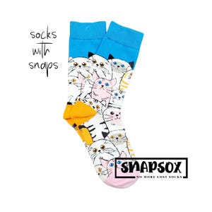 Könnte beinhalten: Ein Paar blaue und weiße Socken mit einem Katzenmuster. Die Socken haben einen rosa Druckknopf oben und der Text "Snapsox No More Lost Socks" ist unten aufgedruckt.