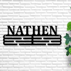 May include: Black metal medal display rack with the name "NATHEN" above it. The rack has five horizontal bars for hanging medals.