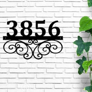 May include: Black metal house number plaque with the number 3856 and a decorative scroll design.