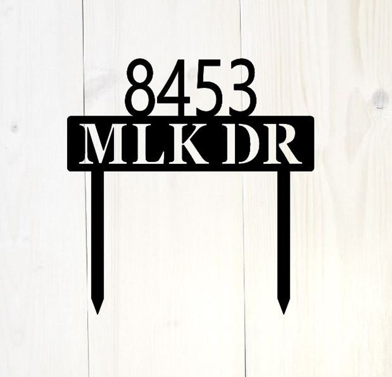 May include: Black metal house number sign with the number 8453 and the name MLKDR in white lettering.