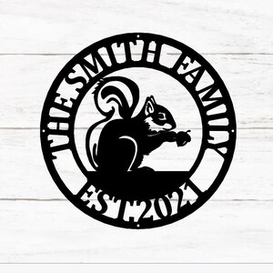 May include: Black metal sign featuring a squirrel holding a nut. The sign reads "The Smith Family Est 2021".