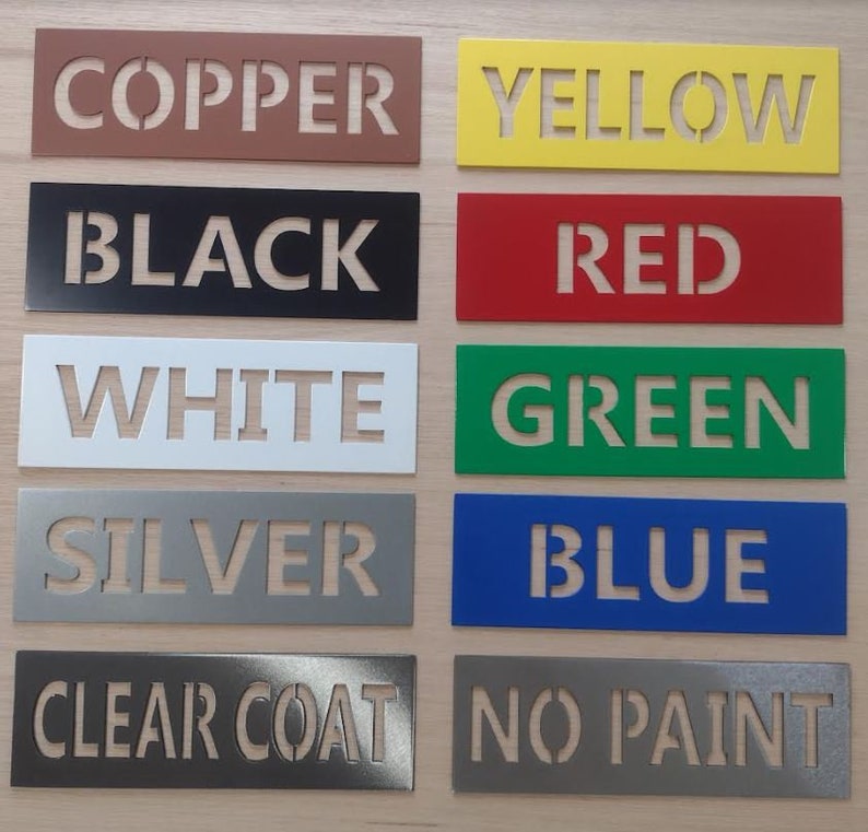 May include: A collection of rectangular metal stencils in various colors, each displaying a different color name in capital letters. Colors include copper, yellow, black, red, white, green, silver, blue, clear coat, and no paint.