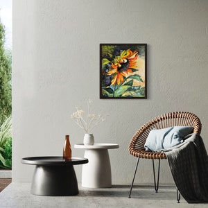 以下が含まれることがあります： オレンジと黄色の花びら、緑の葉、濃い茶色の芯を持つひまわりの絵。ひまわりは濃い茶色の額縁に入っています。