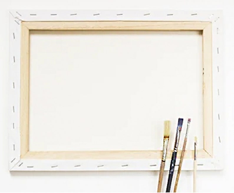 以下が含まれることがあります： 木製のフレームに張られた白いキャンバスは、絵を描く準備ができています。4本の筆がフレームに寄りかかっています。