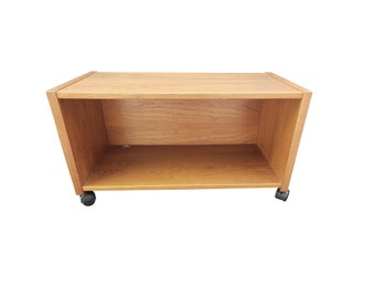 May include: A wooden shelf unit with a single shelf and wheels. The shelf is made of light brown wood and has a simple design.