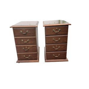 May include: Two wooden file cabinets with four drawers each. The cabinets are a dark brown color and have brass handles. The top of each cabinet has a glass top.