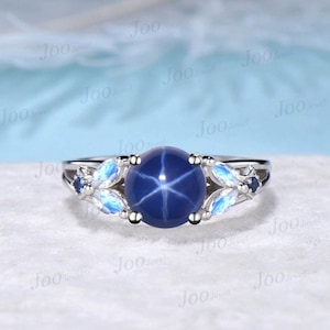 May include: A silver ring with a blue star sapphire gemstone surrounded by smaller white gemstones.