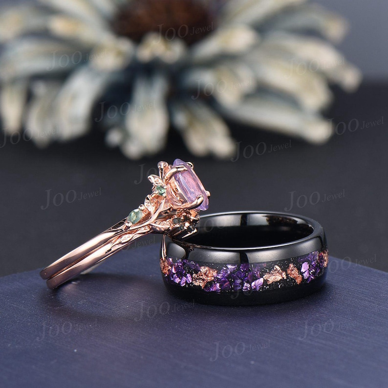 Puede incluir: Dos anillos: un anillo de compromiso de oro rosa con una piedra preciosa p&uacute;rpura y un anillo de banda negro con detalles p&uacute;rpuras y cobrizos. El anillo de compromiso tiene un dise&ntilde;o floral con detalles verdes.