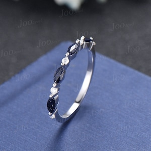 May include: A delicate silver band ring with a row of alternating marquise-shaped blue and round white gemstones.