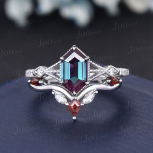 May include: A silver ring set with a large, octagonal, iridescent alexandrite gemstone. The ring is accented with smaller diamonds and red gemstones.