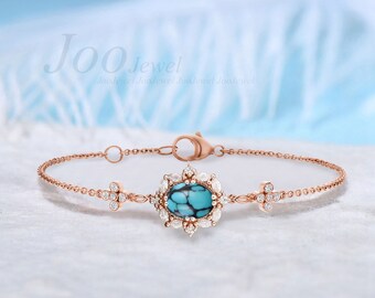 Può includere: Un delicato braccialetto in oro rosa con una pietra turchese circondata da un'aureola di diamanti scintillanti. Il braccialetto presenta un piccolo ciondolo a forma di croce con diamanti su entrambi i lati.