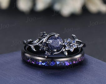 Puede incluir: Un juego de anillos de boda negros. El anillo de compromiso presenta una gema azul redonda grande, con aspecto moteado, rodeada de un diseño floral. La banda a juego tiene un acabado negro con una incrustación moteada azul y morada.