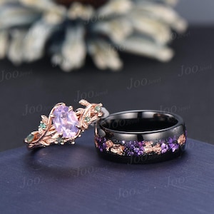 Puede incluir: Dos anillos: un anillo de compromiso de oro rosa con una piedra preciosa ovalada de color p&uacute;rpura claro y detalles verdes, y un anillo de banda negro con detalles florales p&uacute;rpuras y dorados. Los anillos est&aacute;n sobre un fondo azul oscuro.
