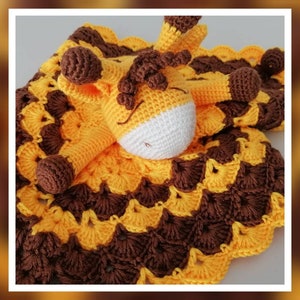 May include: A crocheted giraffe baby blanket with a yellow and brown pattern. The giraffe is lying on the blanket with its head resting on the blanket. The blanket is made with a scalloped edge.