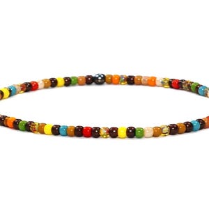 Könnte beinhalten: Ein Armband mit bunten Perlen. Die kleinen, runden Perlen sind in verschiedenen Farben gehalten, darunter Rot, Gelb, Blau, Grün und Braun. Das Armband ist für das Handgelenk konzipiert.