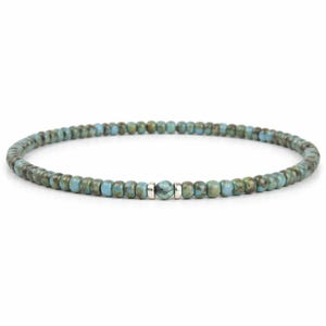 May include: A beaded bracelet featuring small, round turquoise and brown beads. A single, larger turquoise bead is centered, flanked by small silver-colored beads. The bracelet is strung on a flexible cord, suitable for everyday wear.