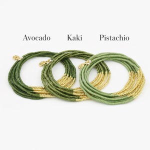 Op de afbeelding: Drie armbanden van kralen in groen- en goudtinten. De armbanden zijn gelabeld met "Avocado", "Kaki" en "Pistache". Elke armband is gemaakt van kleine, ronde kralen en heeft een goudkleurige sluiting.