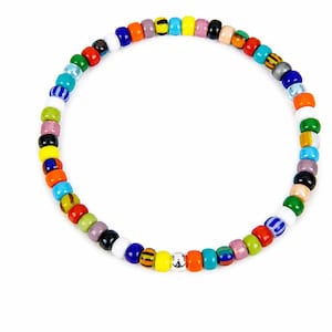 May include: A circular beaded bracelet featuring a variety of small, smooth, multi-coloured glass beads. The strand includes solid colours like red, blue, yellow, green, orange, white, and black, alongside striped and metallic silver beads.