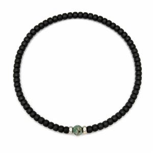 Könnte beinhalten: Schwarze Perlenkette mit einem zentralen türkisfarbenen Stein. Die Halskette besteht aus kleinen, runden, schwarzen Perlen. Der türkisfarbene Stein ist mit silberfarbenem Metall akzentuiert. Die Halskette wird vor weißem Hintergrund gezeigt.
