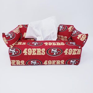 May include: Red and gold tissue box cover with the San Francisco 49ers logo repeated on the fabric.