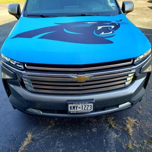 May include: A gray SUV with a blue car cover featuring a black panther logo. The license plate reads "KMY-1223" and "BOB JOHNSON".