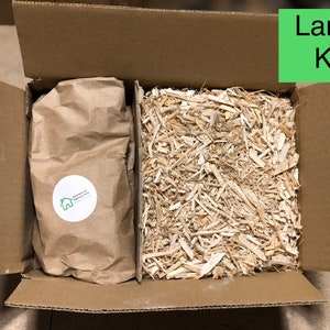 May include: A cardboard box with a brown paper bag and wood shavings inside. The box is labeled "Large Kit".