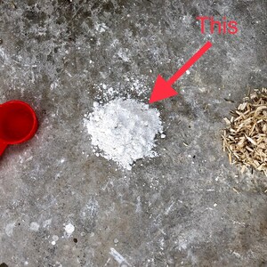 May include: A white powder, a red measuring cup, and wood shavings on a gray concrete surface. The text "This" is written in red above an arrow pointing to the white powder.