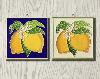 Puede incluir: Dos azulejos de cerámica con fondo azul y verde que presentan un motivo de limón. Los limones son amarillos con hojas verdes y flores blancas.