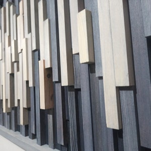 May include: A framed wall art piece made of various wood planks in shades of gray, white, and brown. The planks are arranged in a random pattern, creating a modern and abstract design.