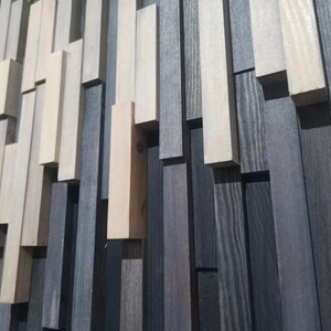 May include: A wall made of various wood planks in shades of gray, brown, and white. The planks are arranged in a staggered pattern, creating a textured and modern look.