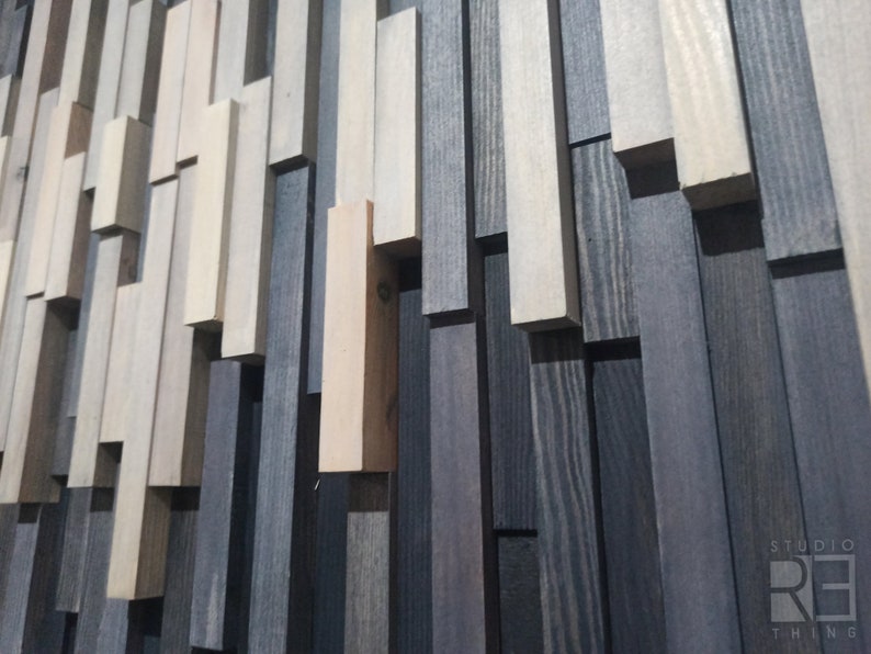 May include: A wall made of various wood planks in shades of gray, brown, and white. The planks are arranged in a staggered pattern, creating a textured and modern look.