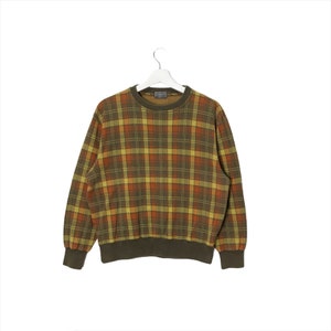 Può includere: Un maglione a maniche lunghe a quadri verde, arancione e giallo.