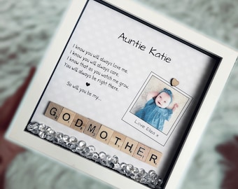 Puede incluir: Un marco blanco con un paspartú negro y una foto de una niña pequeña. El marco tiene un mensaje que dice "Auntie Katie I know you will always love me. I know you will always care. I know that as you watch me grow. You will always be right there. So will you be my... Love Eliza x" y las palabras "GODMOTHER" deletreadas con fichas de letras de madera.