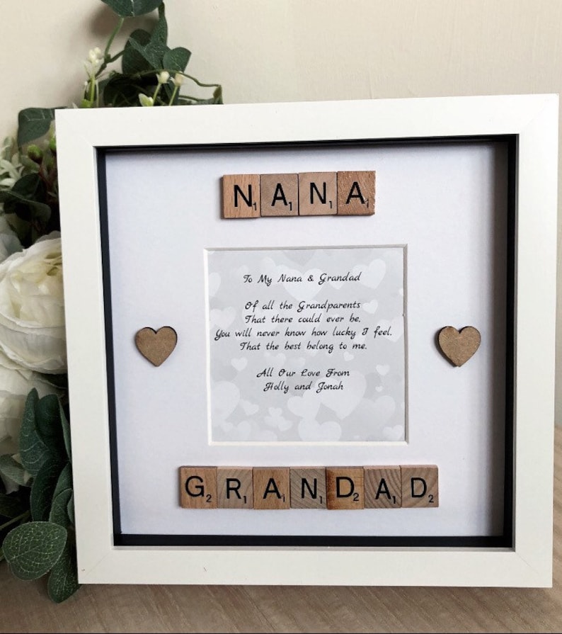 May include: A white picture frame with a black mat and a white background. The frame contains a poem about grandparents, with the words "Nana" and "Grandad" spelled out in wooden letter tiles. The poem reads: "To My Nana & Grandad Of all the Grandparents That there could ever be. You will never know how lucky I feel. That the best belong to me. All Our Love From Holly and Jonah"