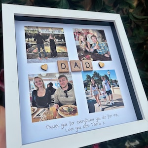 Pode incluir: Uma colagem de fotos emoldurada em branco com quatro fotos, letras de madeira que soletram "DAD" e dois cora&ccedil;&otilde;es de madeira. A parte inferior da colagem tem texto manuscrito: "Thank you for everything you do for me, Love you lots! T Sara x".