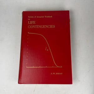 Könnte beinhalten: Ein rotes Lehrbuch mit dem Titel "Society of Actuaries' Textbook on Life Contingencies" in goldener Schrift und einer Grafik. Der Name des Autors, C. W. Jordan, ist unten aufgedruckt. Das Buch ist in gutem Zustand.