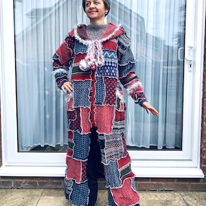 May include: A patchwork coat in red, blue, and white. The long coat features a hood and is made of various knitted and woven fabrics. The coat has a unique, textured appearance with a mix of patterns and textures, creating a cozy and artistic look.