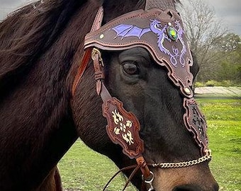 May include: A brown leather horse headstall with a purple and green dragon design. The headstall has a decorative noseband and browband with intricate floral patterns.