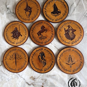 May include: Eight round wooden coasters with engraved designs and dark brown borders. The designs include a wizard, a horse, and other fantasy symbols. One coaster has the text "Dancing Pony". The coasters are made of wood.