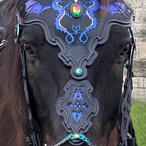 May include: A black leather horse bridle with blue and silver dragon accents. The bridle features a large, iridescent gemstone in the center. The text "Fangornranch.com" is visible in the lower left corner of the image.