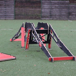 May include: A black and red wooden agility obstacle course for dogs. The course features a series of ramps and jumps.