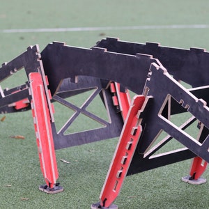 May include: A black and red wooden obstacle course for dogs. The course is made of plywood and has a series of ramps and jumps.